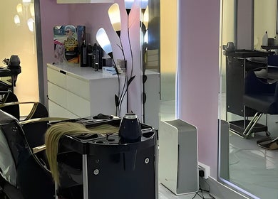 Modern salon interior at Hello Dolly Beauty Center, Doha, Doha Municipality, QA with sleek chairs and vibrant lighting.