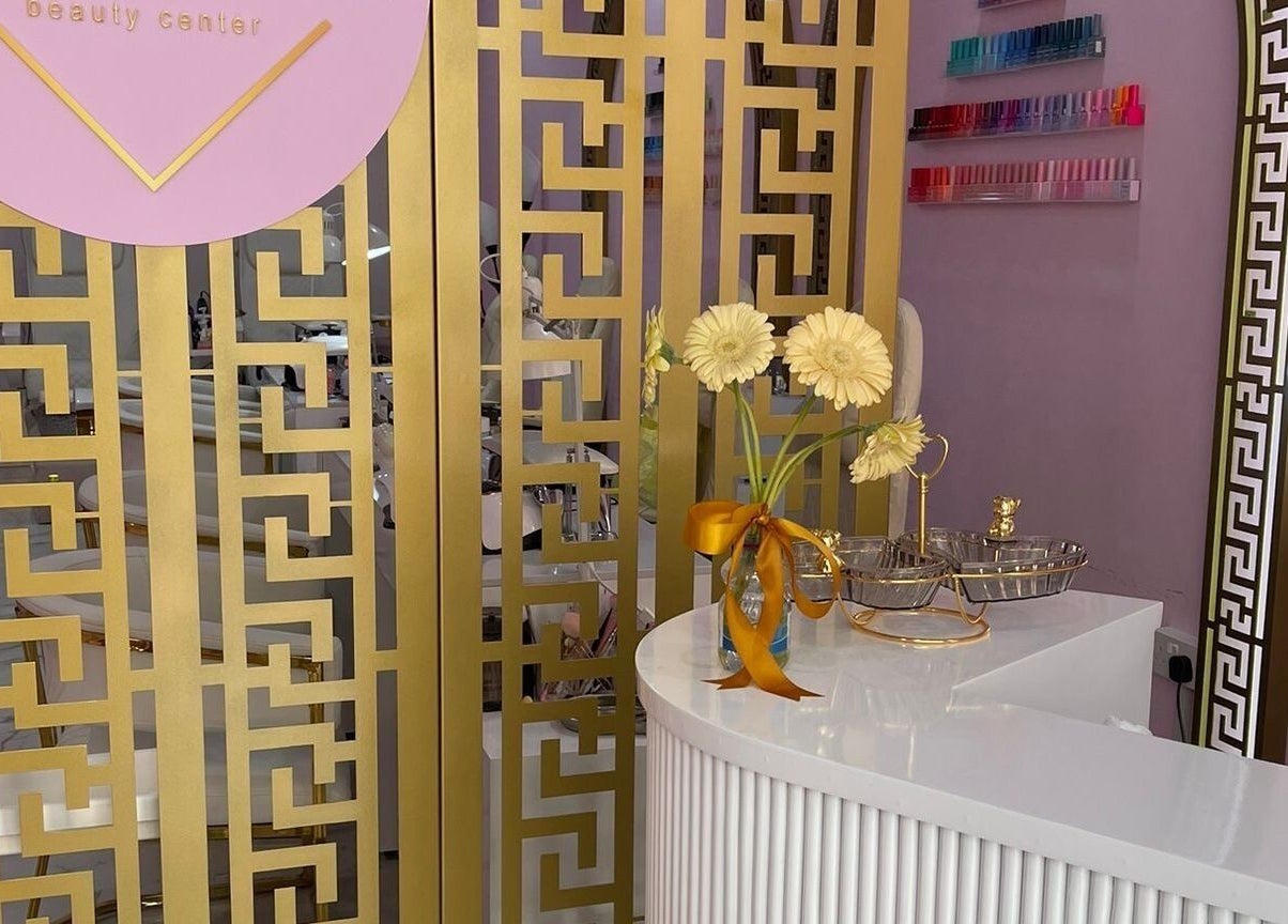 Elegant entrance of Hello Dolly Beauty Center in Doha features a golden screen and white counter.