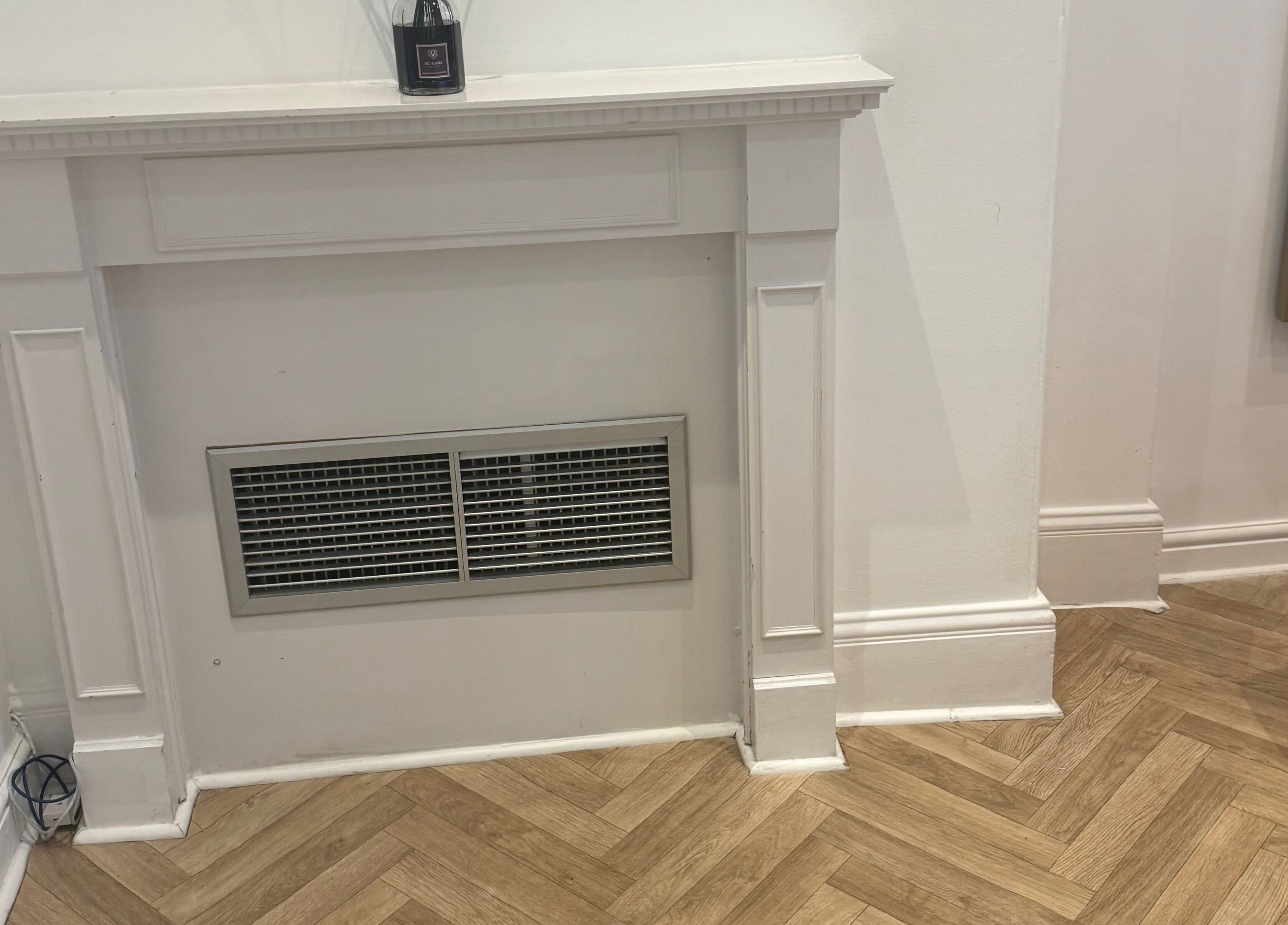 A stylish fireplace at Balanced Sculpt, Birmingham, England, GB, featuring chic decor and herringbone flooring.