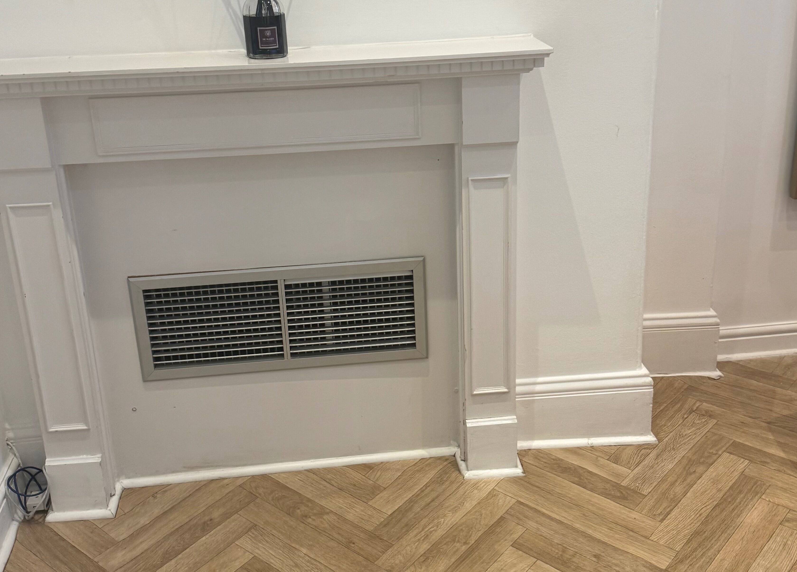 A stylish fireplace at Balanced Sculpt, Birmingham, England, GB, featuring chic decor and herringbone flooring.