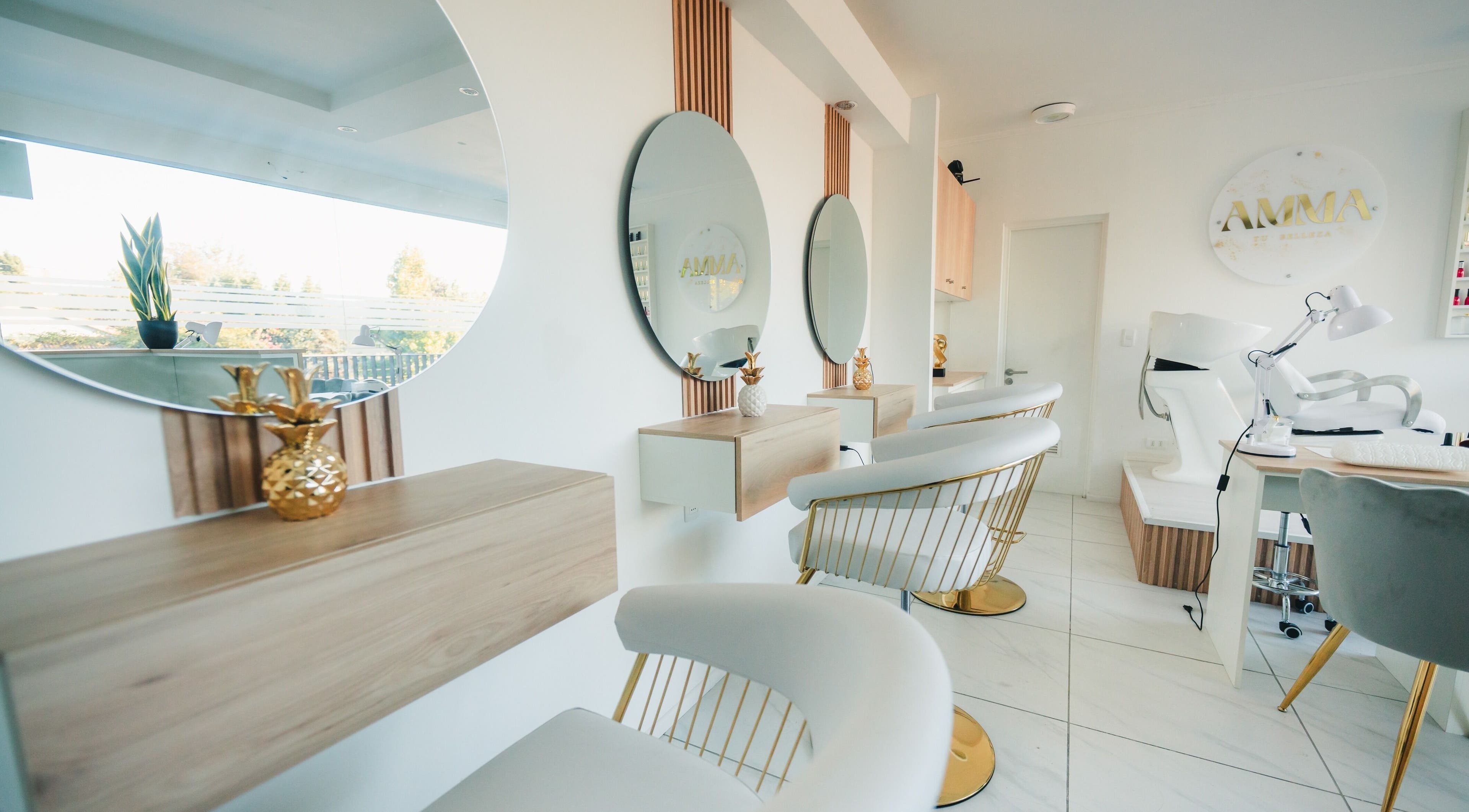 Interior moderno de Amma en Quilpué, Valparaíso, CL, con espejos redondos y sillas blancas elegantes.