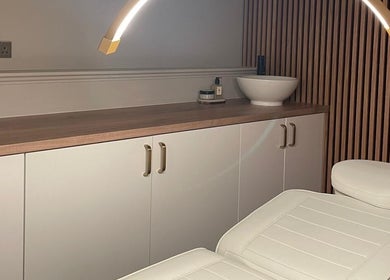 Serene treatment room at Aura Beauty in Aberdeen, Scotland, GB with a plush chair and elegant lighting.