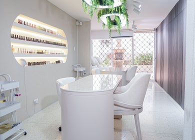 Salón moderno en Fiore studio, Barranquilla, Atlántico, CO. Mobiliario blanco y estantes de esmaltes expuestos.