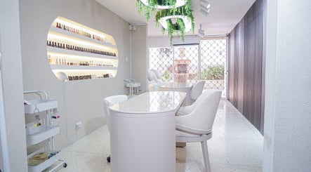 Salón moderno en Fiore studio, Barranquilla, Atlántico, CO. Mobiliario blanco y estantes de esmaltes expuestos.