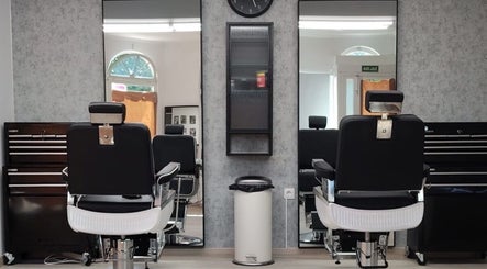Interior moderno de Yutori Barberia en A Coruña, ES con sillas de peluquería negras y espejos amplios.