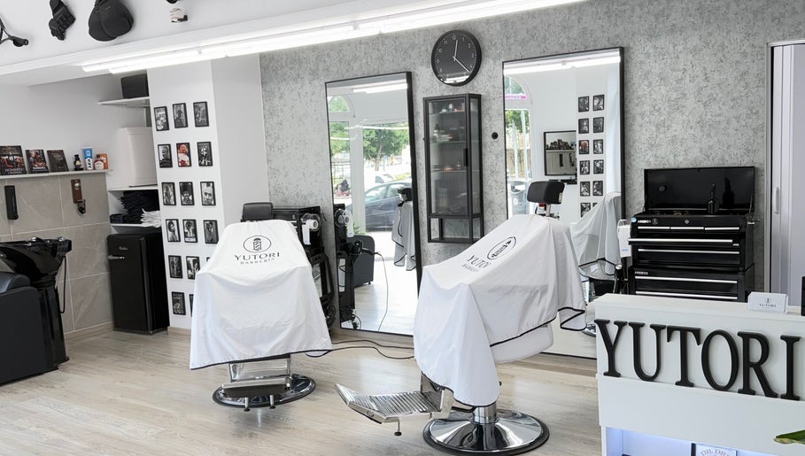 Interior moderno de Yutori Barberia en A Coruña, ES con sillas de peluquería y espejo grande.