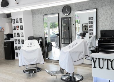 Interior moderno de Yutori Barberia en A Coruña, ES con sillas de peluquería y espejo grande.