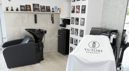 Interior de Yutori Barberia en A Coruña, ES, mostrando sillón y lavacabezas modernos.