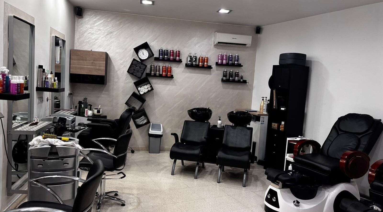 Interior moderno del Salón De Belleza Quezia en Sabadell, Catalunya, ES, con estaciones de peluquería y productos.