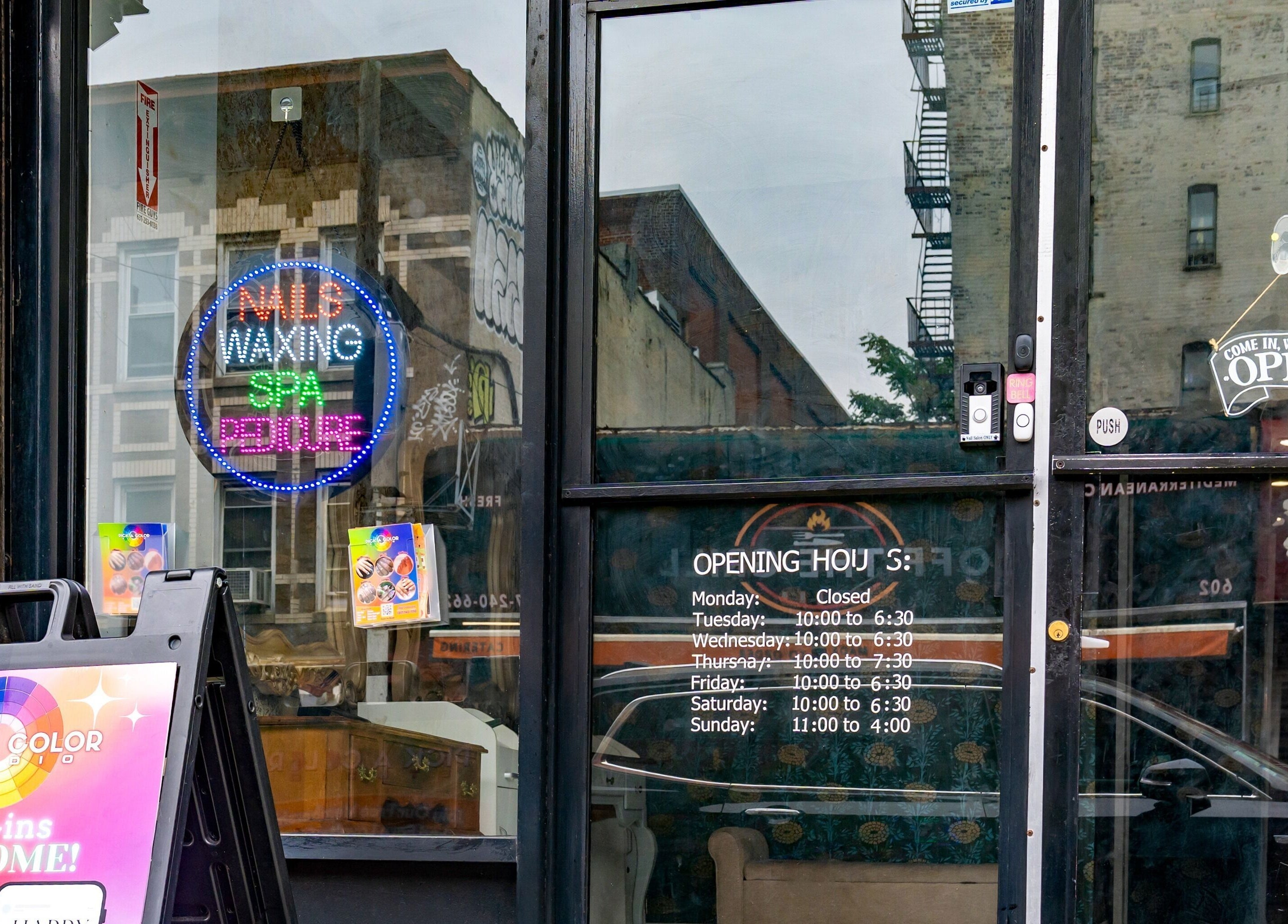 Entrance to Pick A Color Studio, a nail salon in New York, New York, US, featuring colorful signage and business hours.