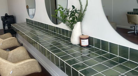 Elegant green tiled counter at Jessi Do My Hair in Dee Why, New South Wales, AU with chairs and decor.