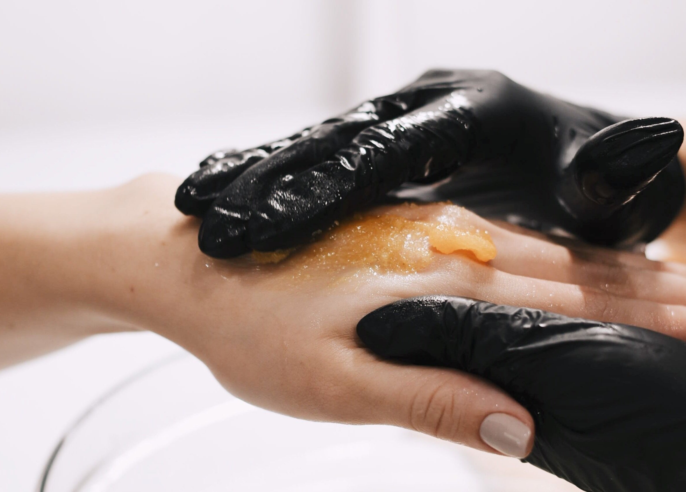 Exfoliación de manos profesional en Momu, Madrid, Comunidad De Madrid, ES, con guantes negros y producto natural.