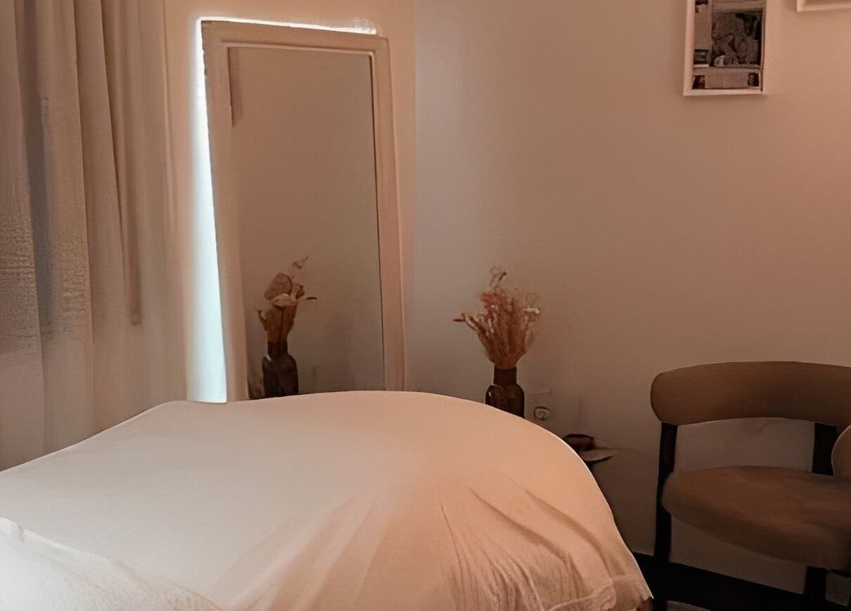 Salle de soins relaxante chez Hoanity à Pontoy, Grand Est, FR. Lit en draps blancs et décor apaisant.