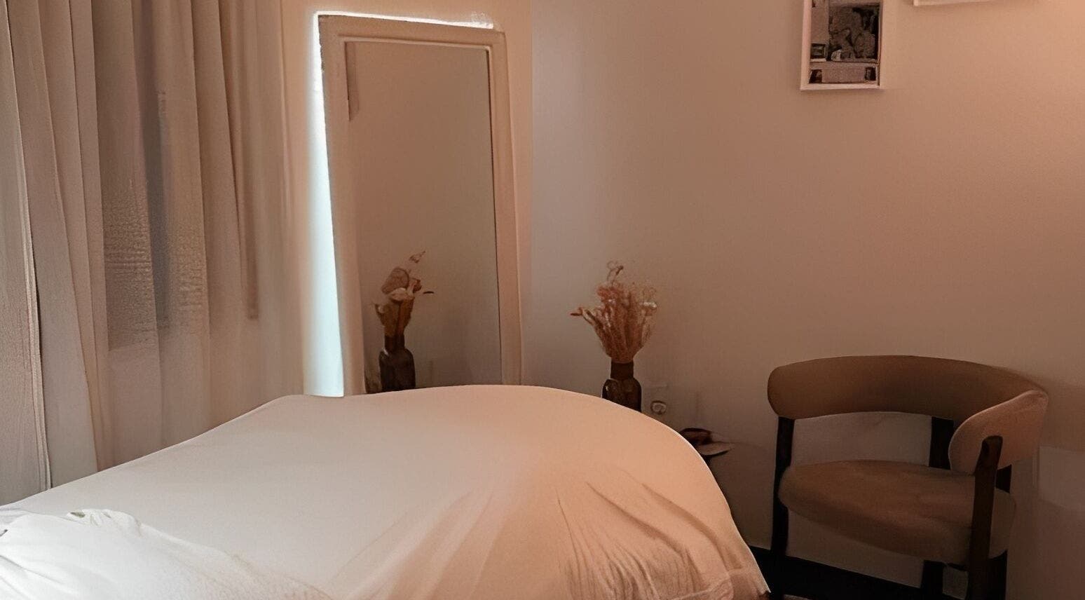 Salle de soins relaxante chez Hoanity à Pontoy, Grand Est, FR. Lit en draps blancs et décor apaisant.