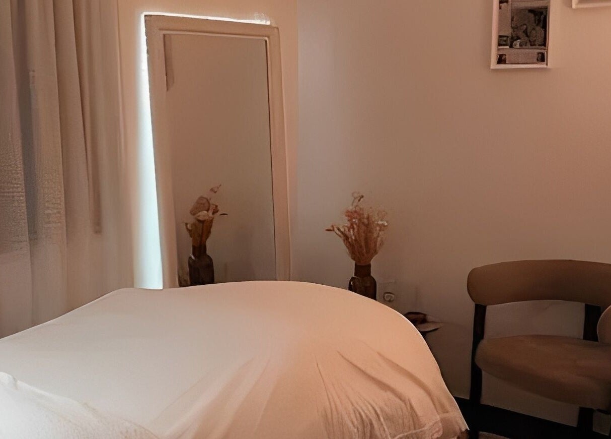 Chambre de soins apaisante chez Hoanity, Pontoy, Grand Est, FR, avec lit et chaise élégante.