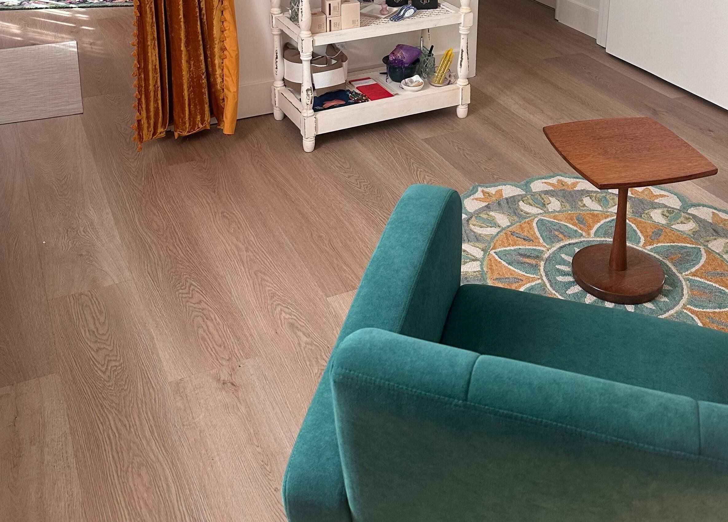 Cozy seating area at Donna Cherie Aesthetics in Santa Cruz, California, US with a teal chair and wooden table.