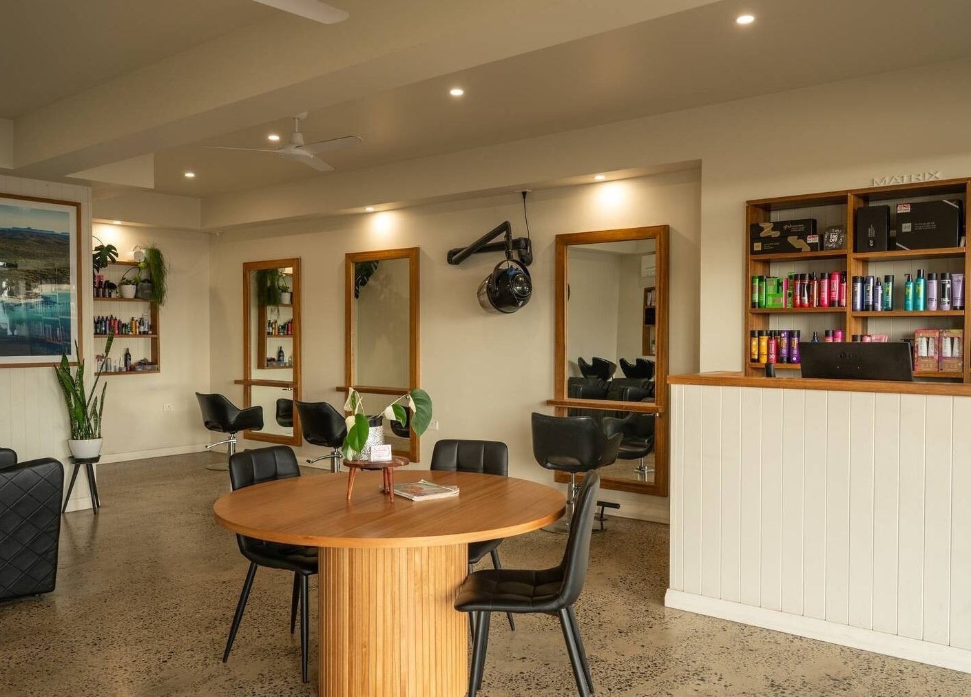 Spacious interior of Beachcomber Hairsalon in Ulladulla, New South Wales, AU, featuring stylish chairs and shelves of products.