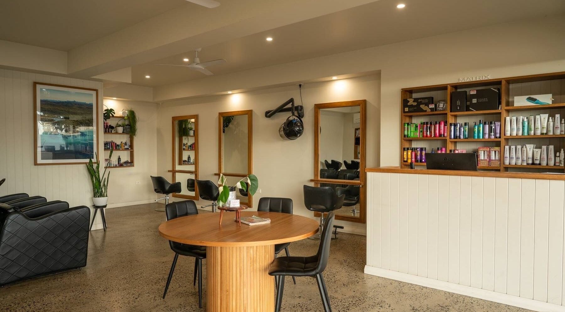 Spacious interior of Beachcomber Hairsalon in Ulladulla, New South Wales, AU, featuring stylish chairs and shelves of products.