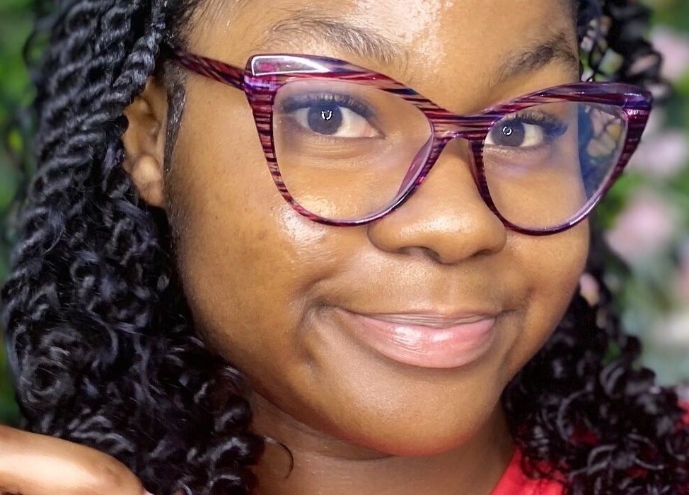 Smiling woman with stylish glasses at The Hair Topic in Portmore, St. Catherine Parish, JM.