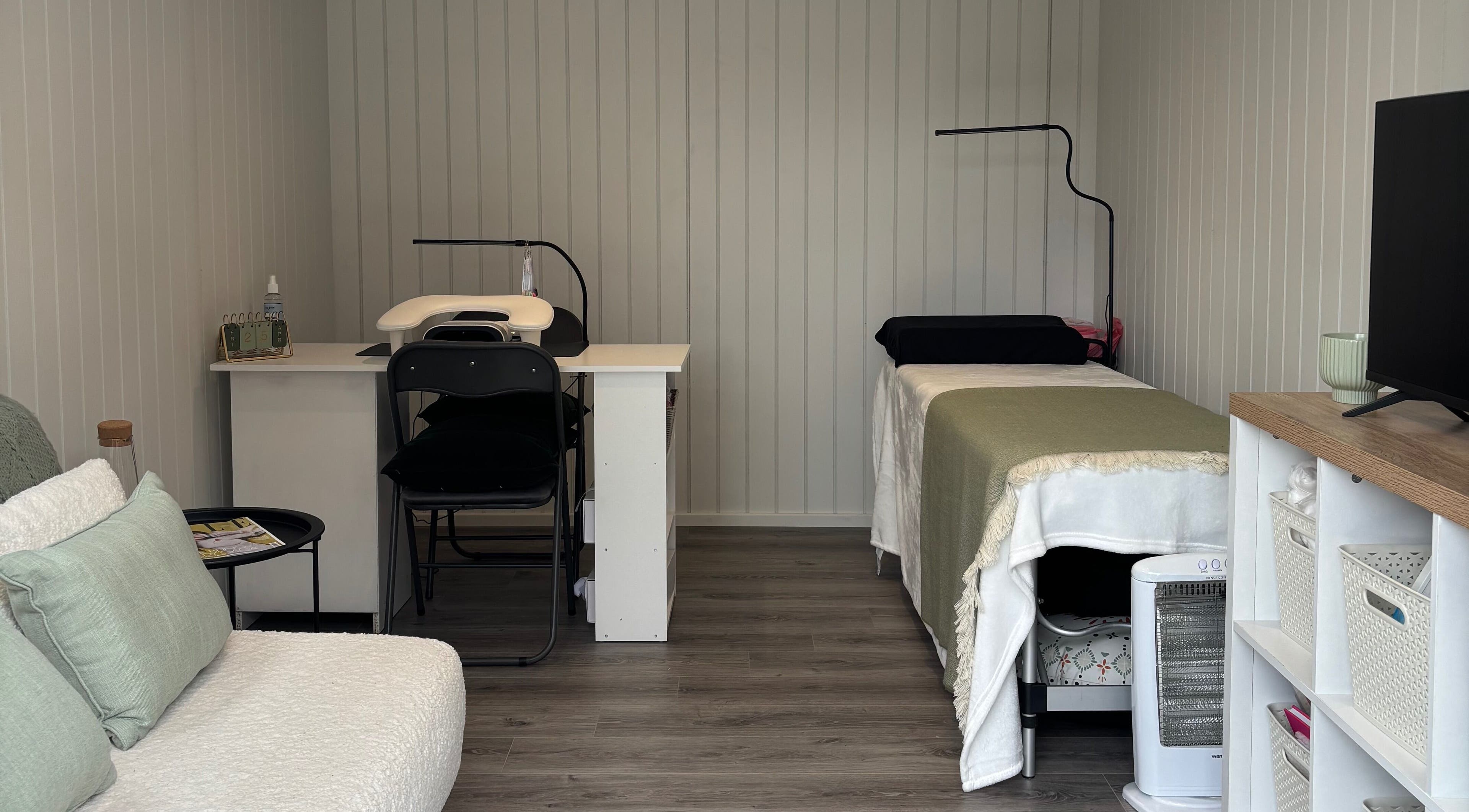 Cozy treatment room at The Beauty Cabin, Royal Leamington Spa, England, GB featuring a massage bed and seating area.