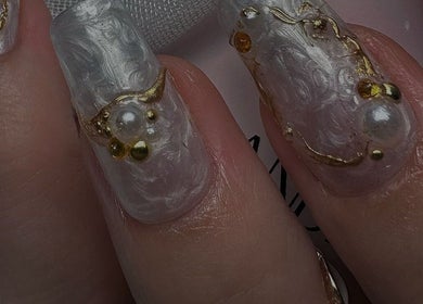 Intricate white nails with pearl and gold accents at 27 De Nails, Marbella, Andalucía, ES.