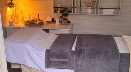 Cozy massage room at Belle Lily Beauty, Aspley Guise, England, GB with warm lighting and plush towels.