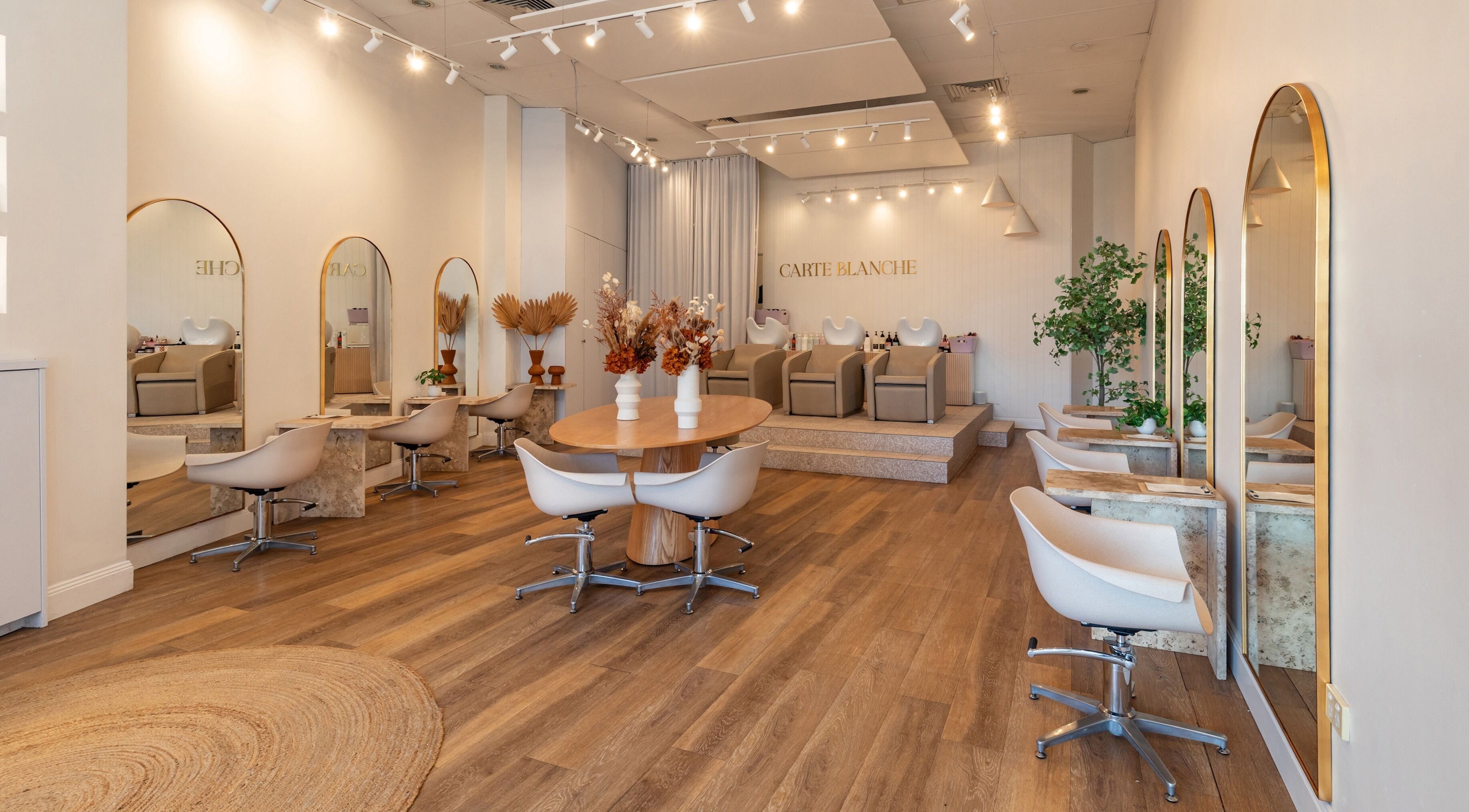 Modern interior of Carte Blanche Hair salon in Seaforth, AU with chic mirrors and stylish chairs.