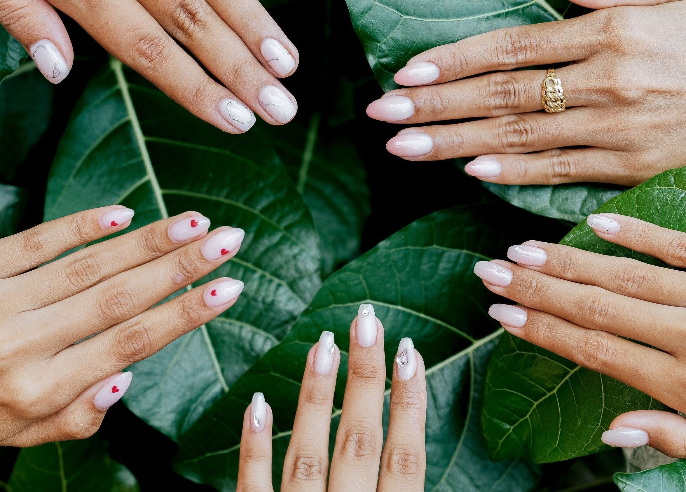 Elegant nail art on hands over green leaves at Sugarbombwax Bali, Bali, ID, showcasing natural beauty.