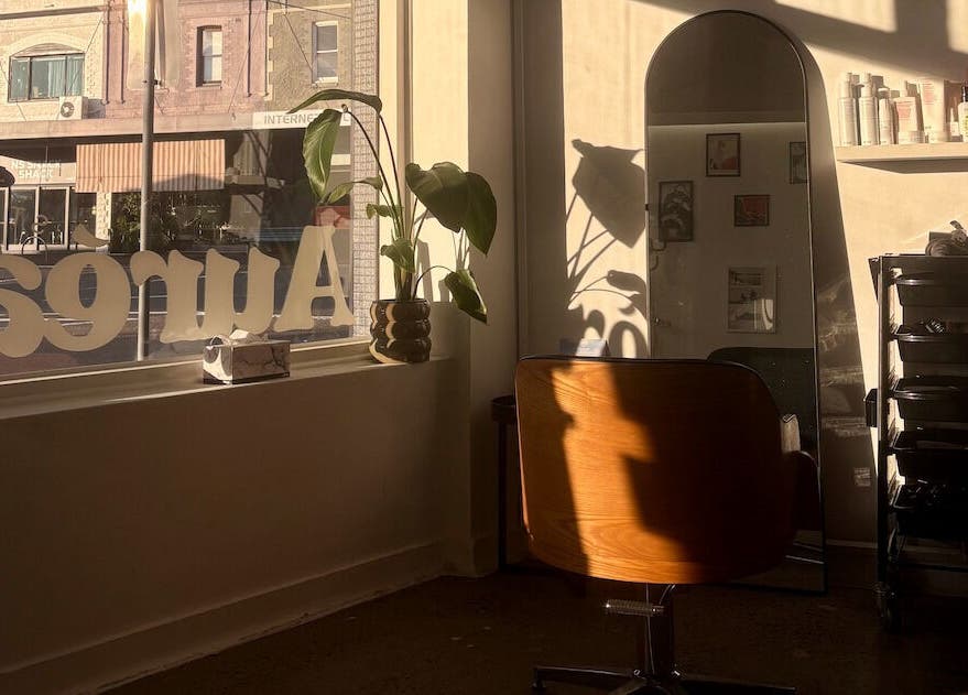 Warmly lit salon chair and mirror at Auréa Studios, Manly, New South Wales, AU. Modern and inviting decor.