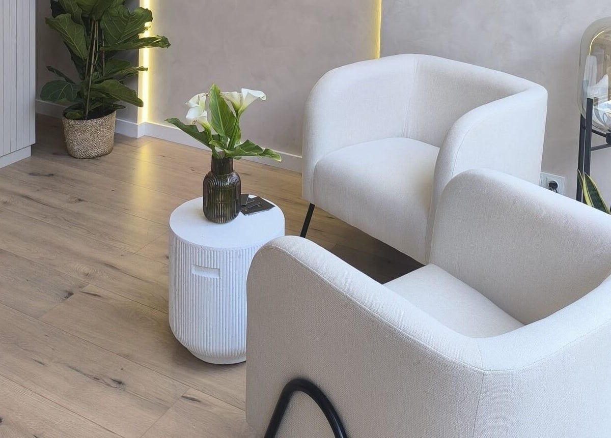 Acogedora sala de espera en Mahō Estilistas, Plaja d'Aro, Catalunya, ES, con sillones blancos y plantas.