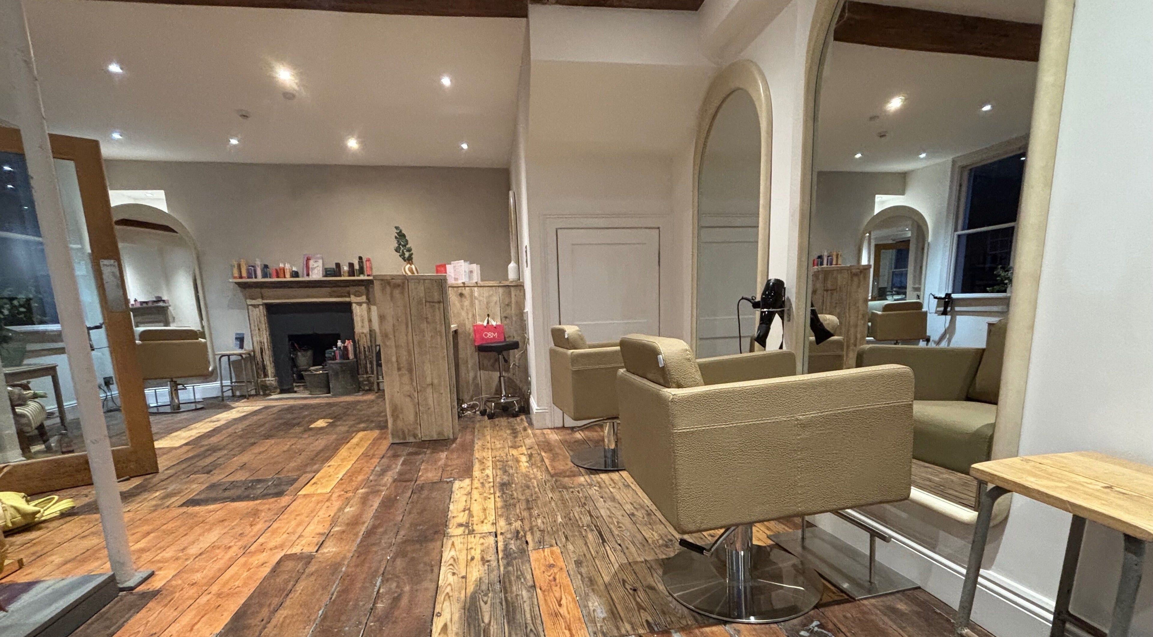 Elegant interior of Folly & Hue Hair And Beauty Studio in Bradford-on-Avon, England. Cozy chairs and rustic decor.