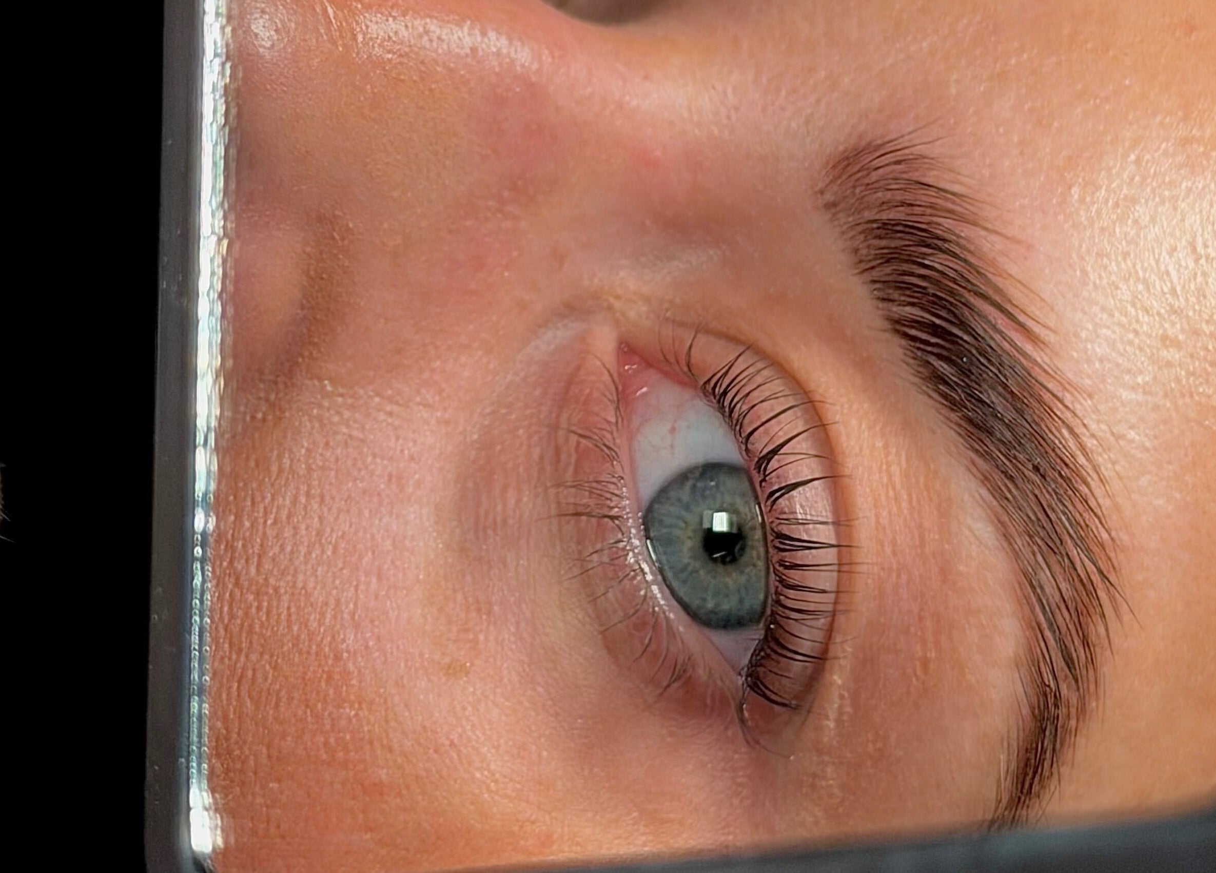 Close-up of perfectly shaped eyebrow and lashes reflection at Mani’s by Millie May, Bridgend, Wales, GB.