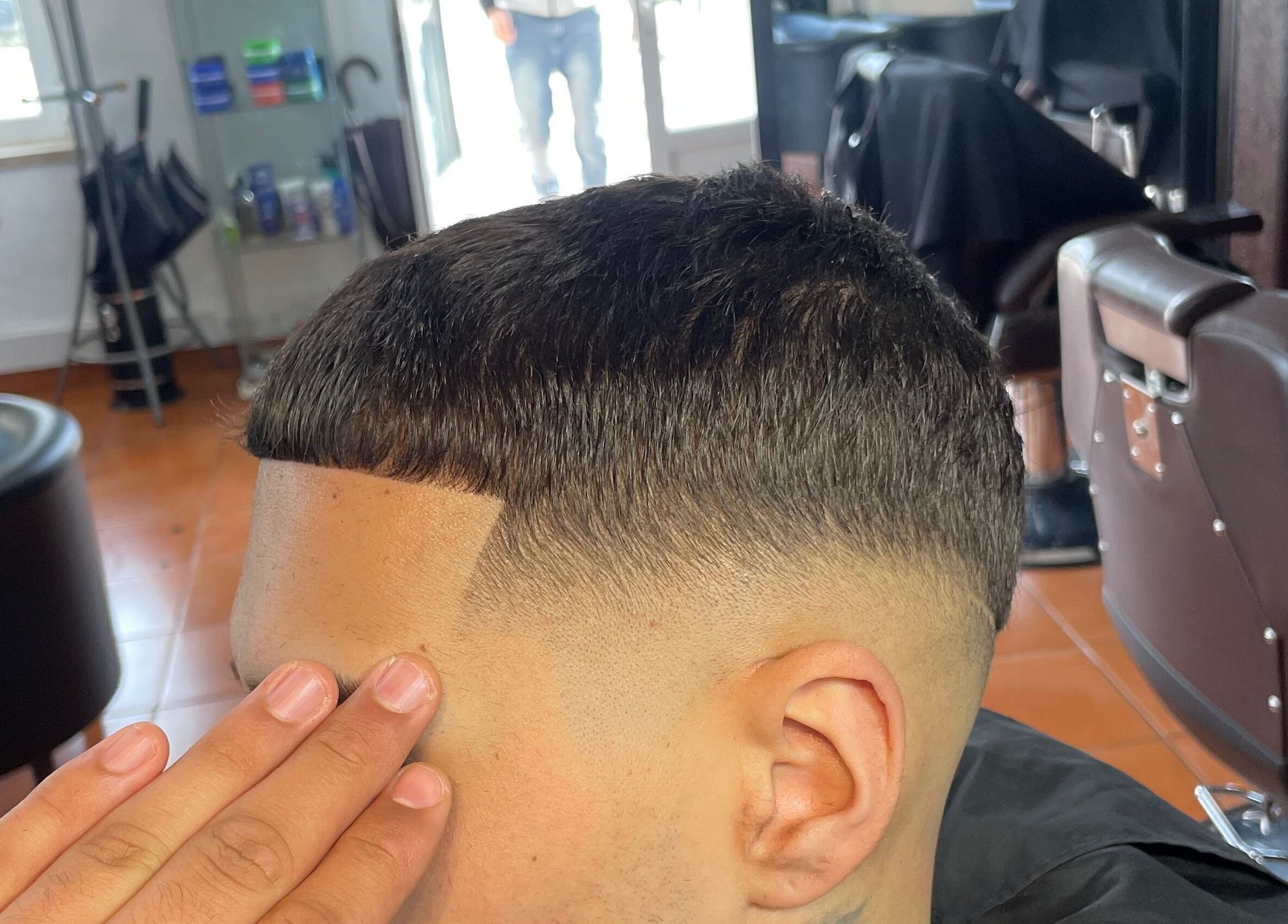 Barbeiro finalizando corte masculino no PASSARO BARBER, Alcabideche, Lisboa, PT.