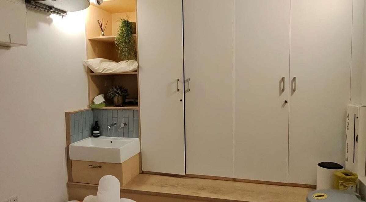 Cozy JM Massage Therapy room with sink and greenery in London, England, GB, offering relaxation and care.