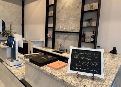 Elegant reception area at Q @ E-Luxe Nail Spa, League City, Texas, US showcasing modern design and soft opening sign.