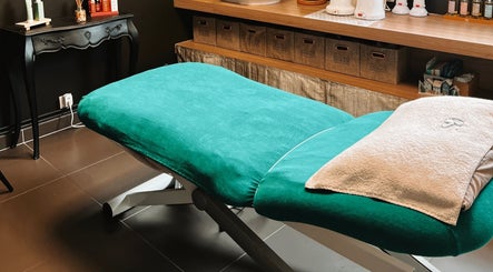 Table de massage verte à L'Atelier du Bien-Etre, Saint-vigor-d'ymonville, Normandie, FR, encadrée par des produits.