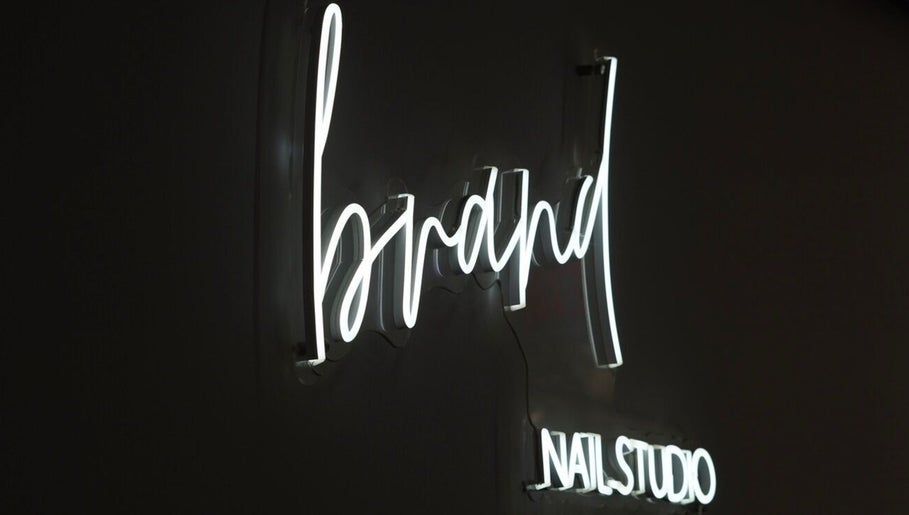 Illuminated neon sign of Brand Nail Studio in Philadelphia, Pennsylvania, US on a dark background.