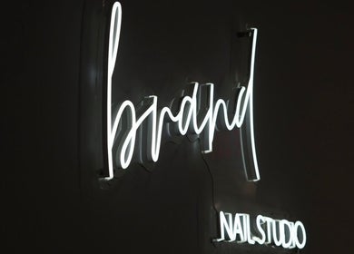 Illuminated neon sign of Brand Nail Studio in Philadelphia, Pennsylvania, US on a dark background.