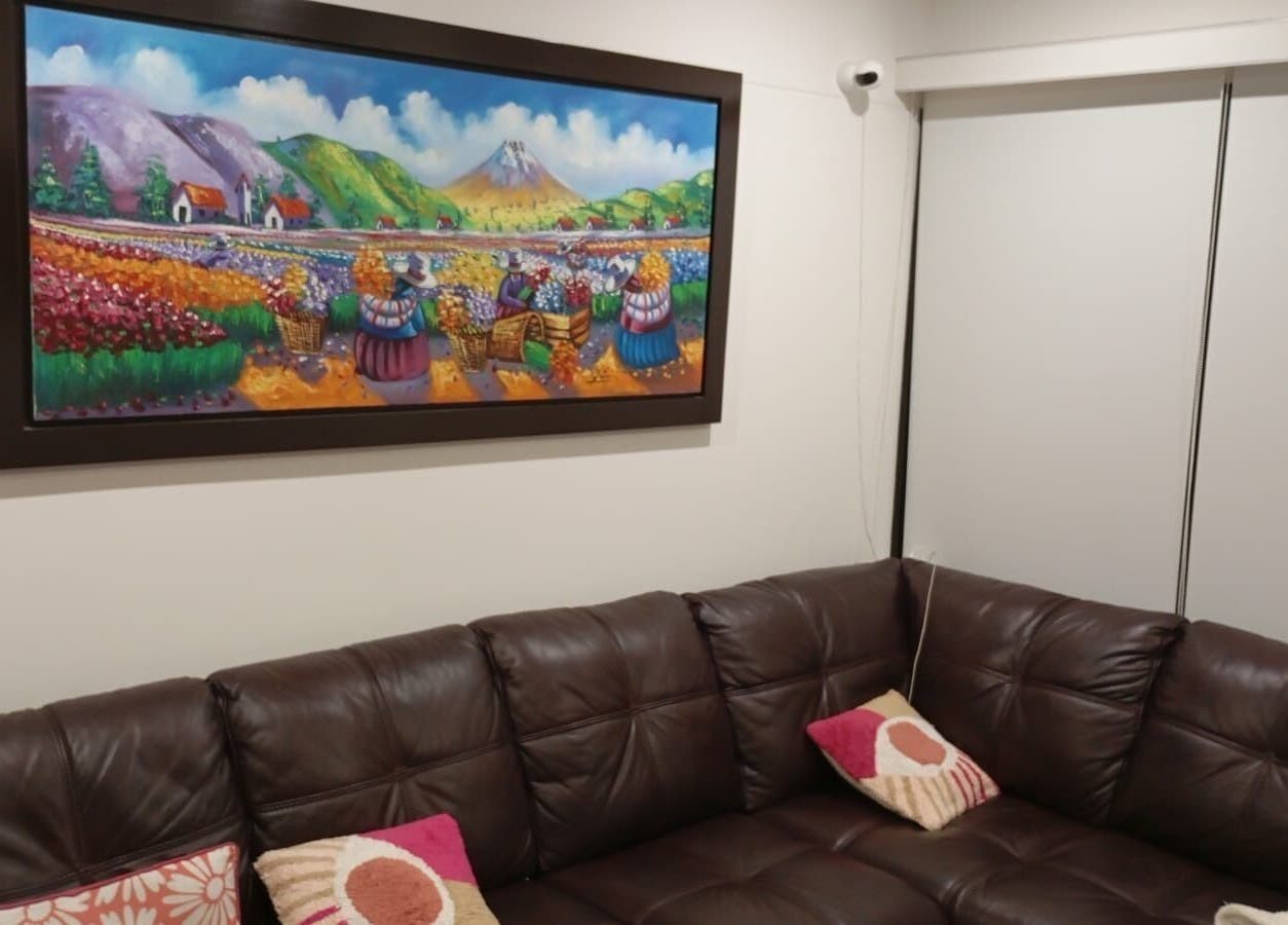 Sala en Elyzea, Miraflores con sofá de cuero y pintura colorida en la pared.
