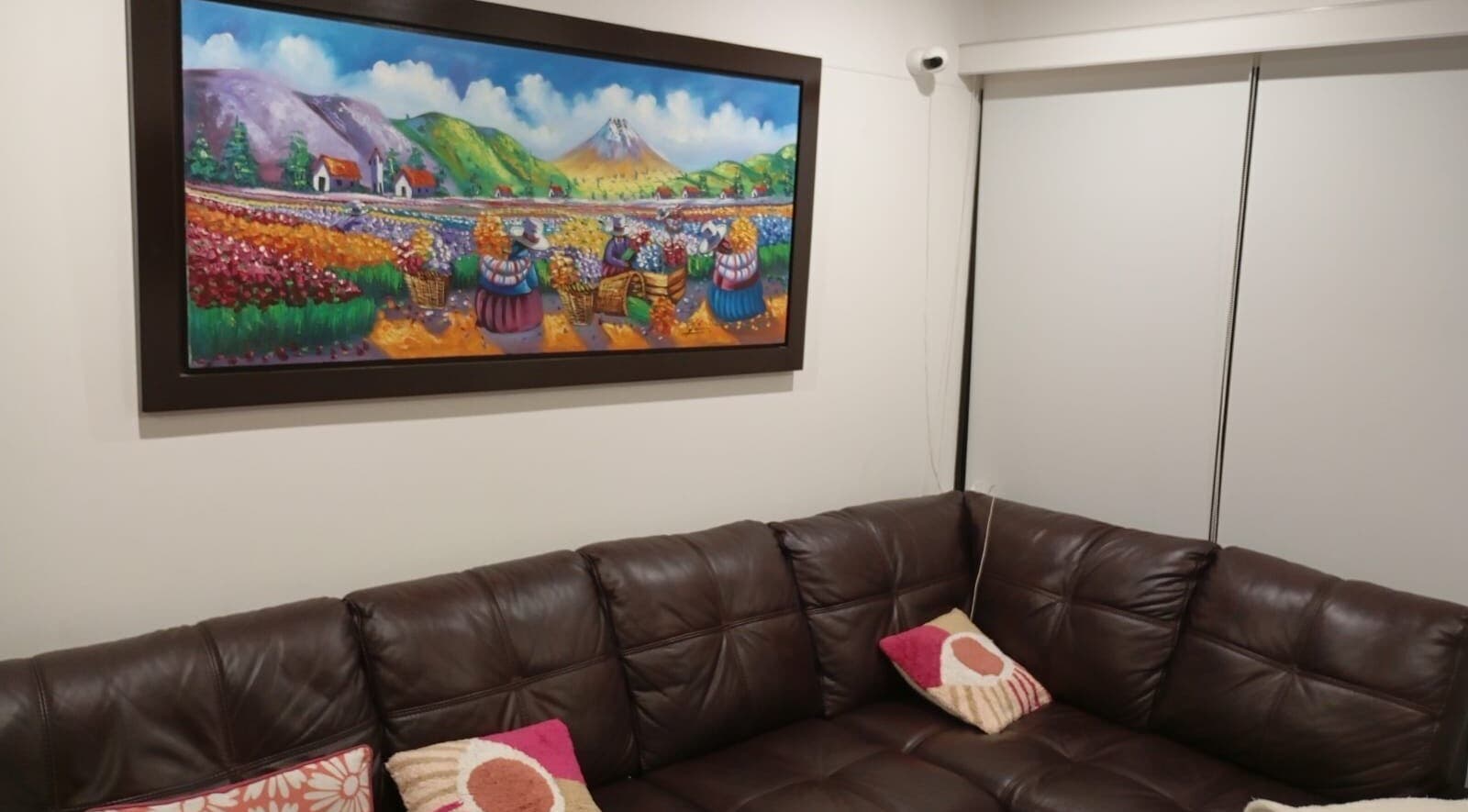 Sala en Elyzea, Miraflores con sofá de cuero y pintura colorida en la pared.