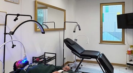 Client receiving LED treatment at Glow.Theoryco, Milton Keynes, England. Modern wellness setup visible.