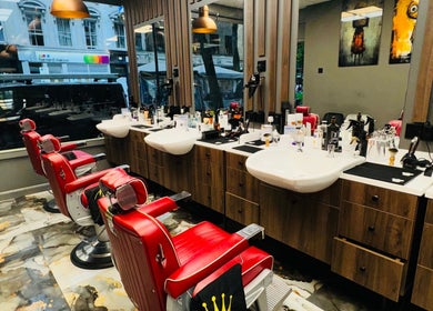 Red barber chairs in stylish 2 Chairs Grooming Room, London, England, GB reflecting modern elegance.