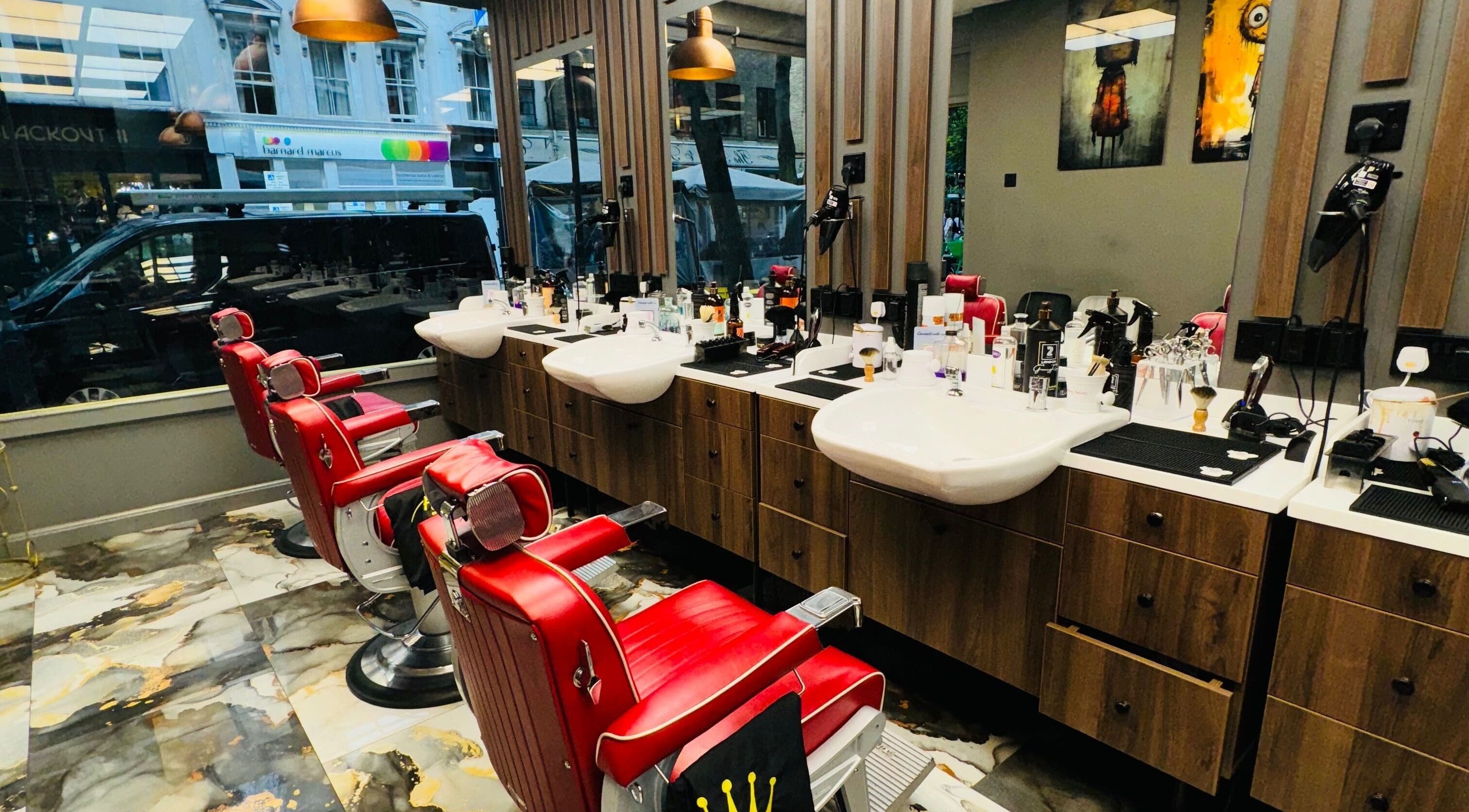 Red barber chairs in stylish 2 Chairs Grooming Room, London, England, GB reflecting modern elegance.