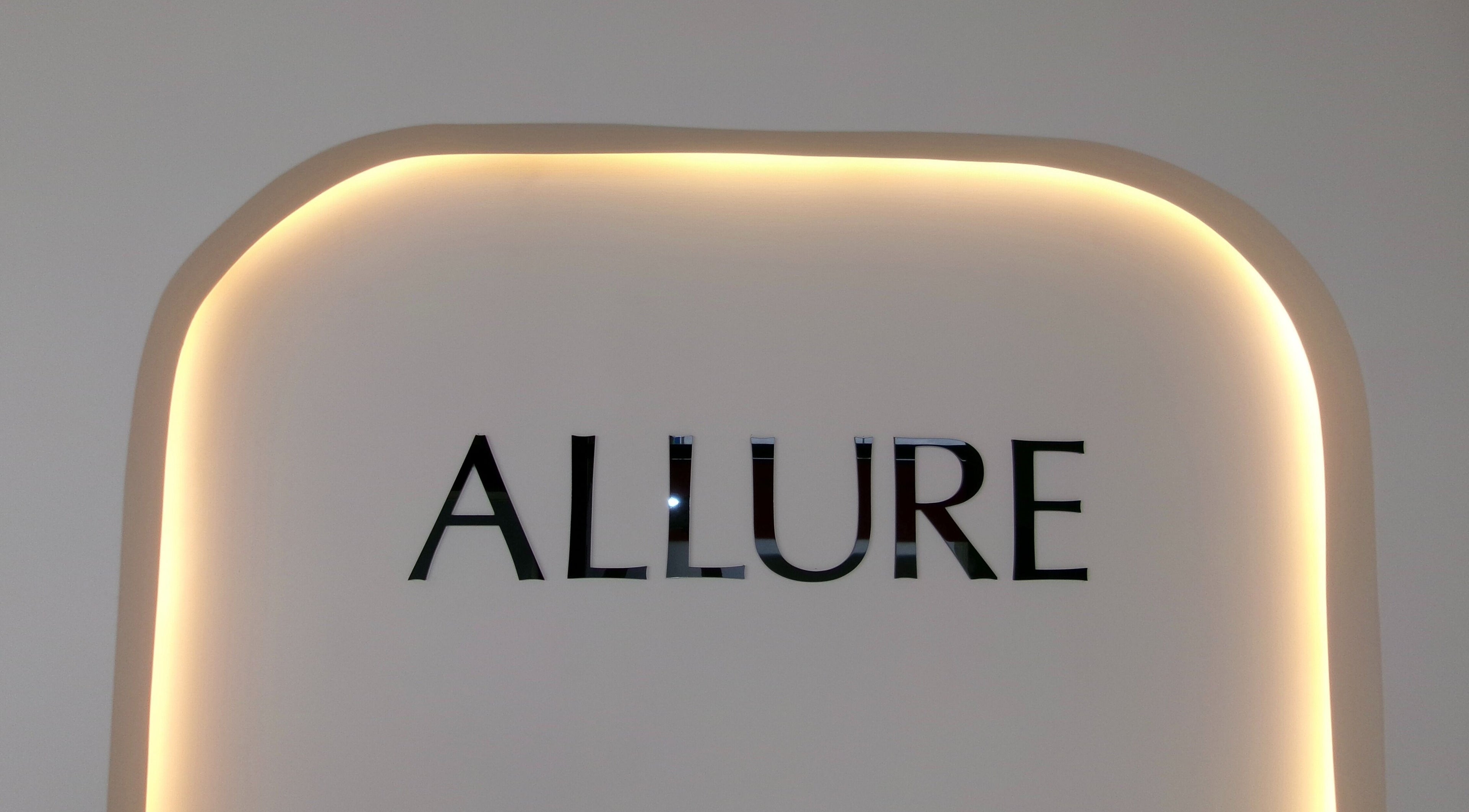 Illuminated logo of Allure Nail Salon & Spa Ashburn in Ashburn, Virginia, US against a stylish backdrop.