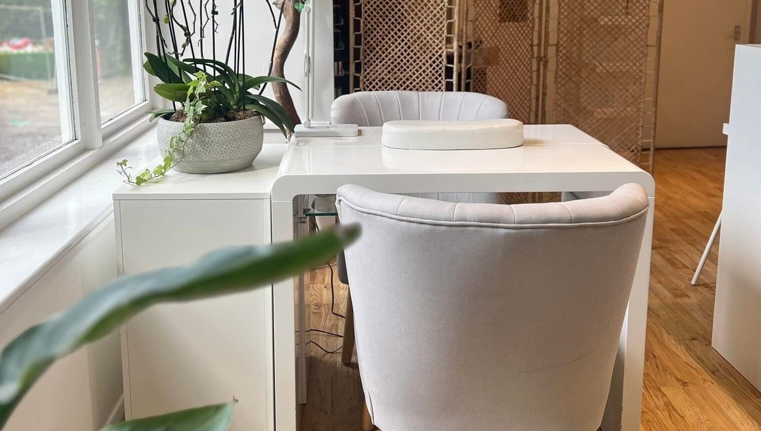 Elegant manicure station at Oval & Arch at Nuve Clinic, Cranbrook, England, GB, featuring plush chairs and plants.