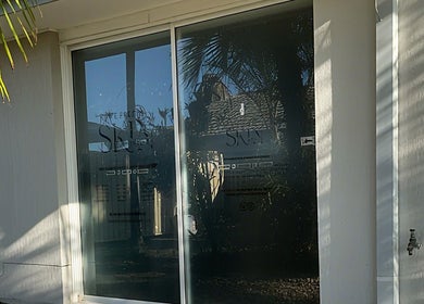 Entrance of The Pretty Skin Society in Warana, Queensland, AU, featuring modern glass doors.