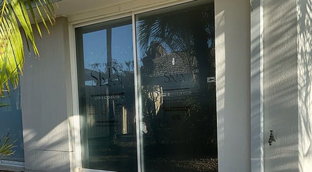 Entrance of The Pretty Skin Society in Warana, Queensland, AU, featuring modern glass doors.