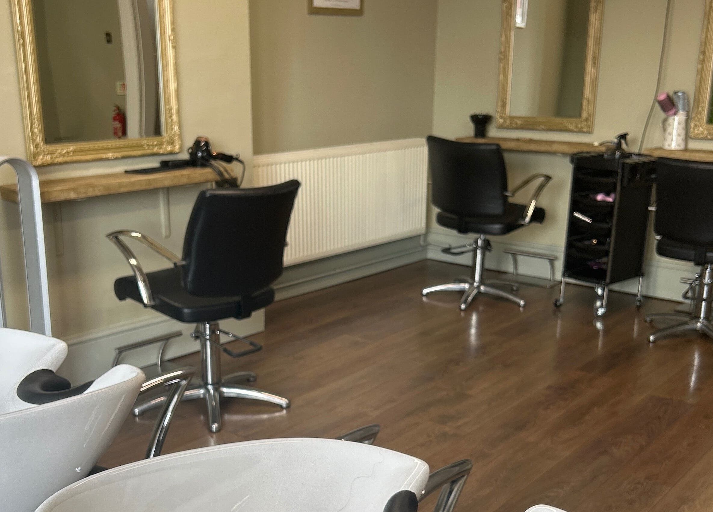 Modern styling area at SC Hair Design, Thirsk, England with sleek black chairs and mirrors