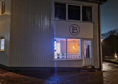 B the barber at night in Tórshavn, Streymoyar, FO with vibrant lighting and stylish entrance.