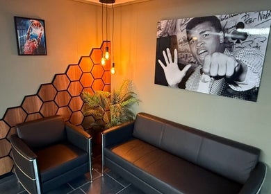 Modern waiting area at B the Barber, Tórshavn, Streymoyar, FO with leather seating and artistic decor.